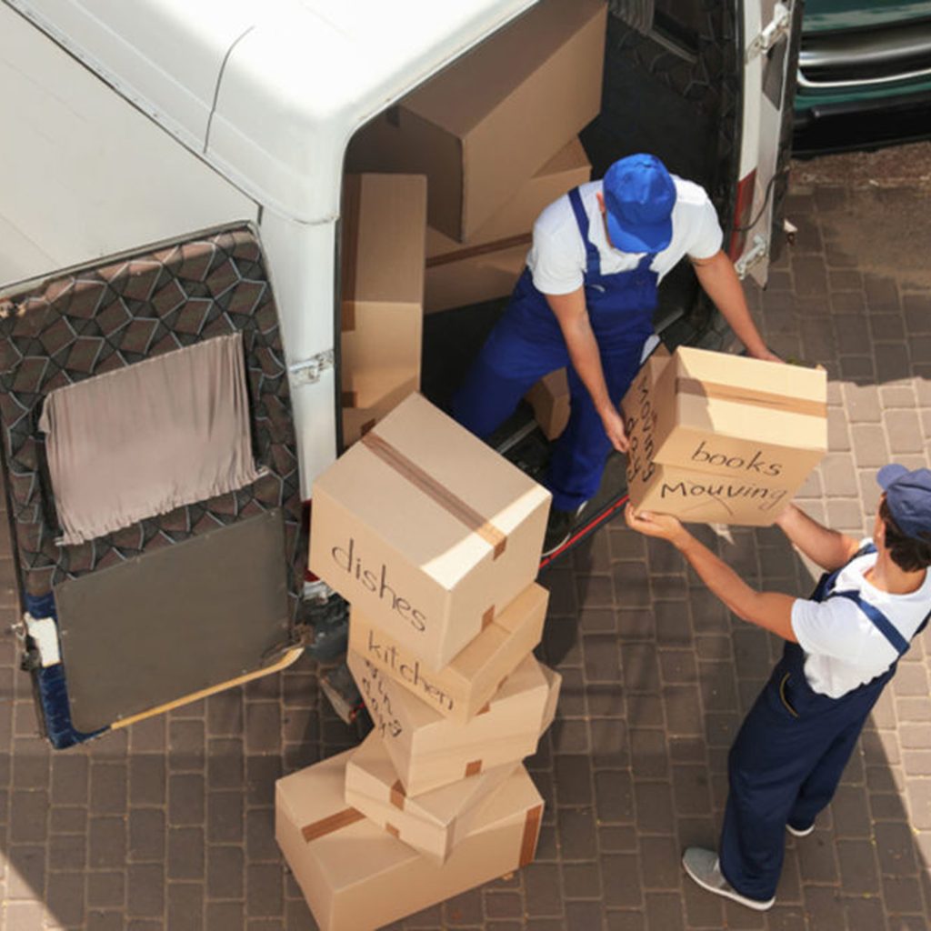 Two professional movers in Dubai carrying boxes from a truck.