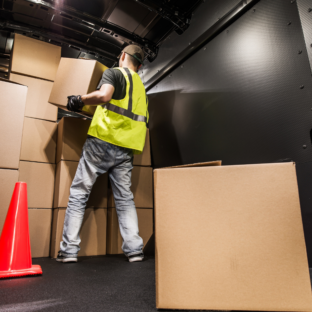 Man in a safety vest loading boxes into a cargo van for cargo to Pakistan from Dubai.