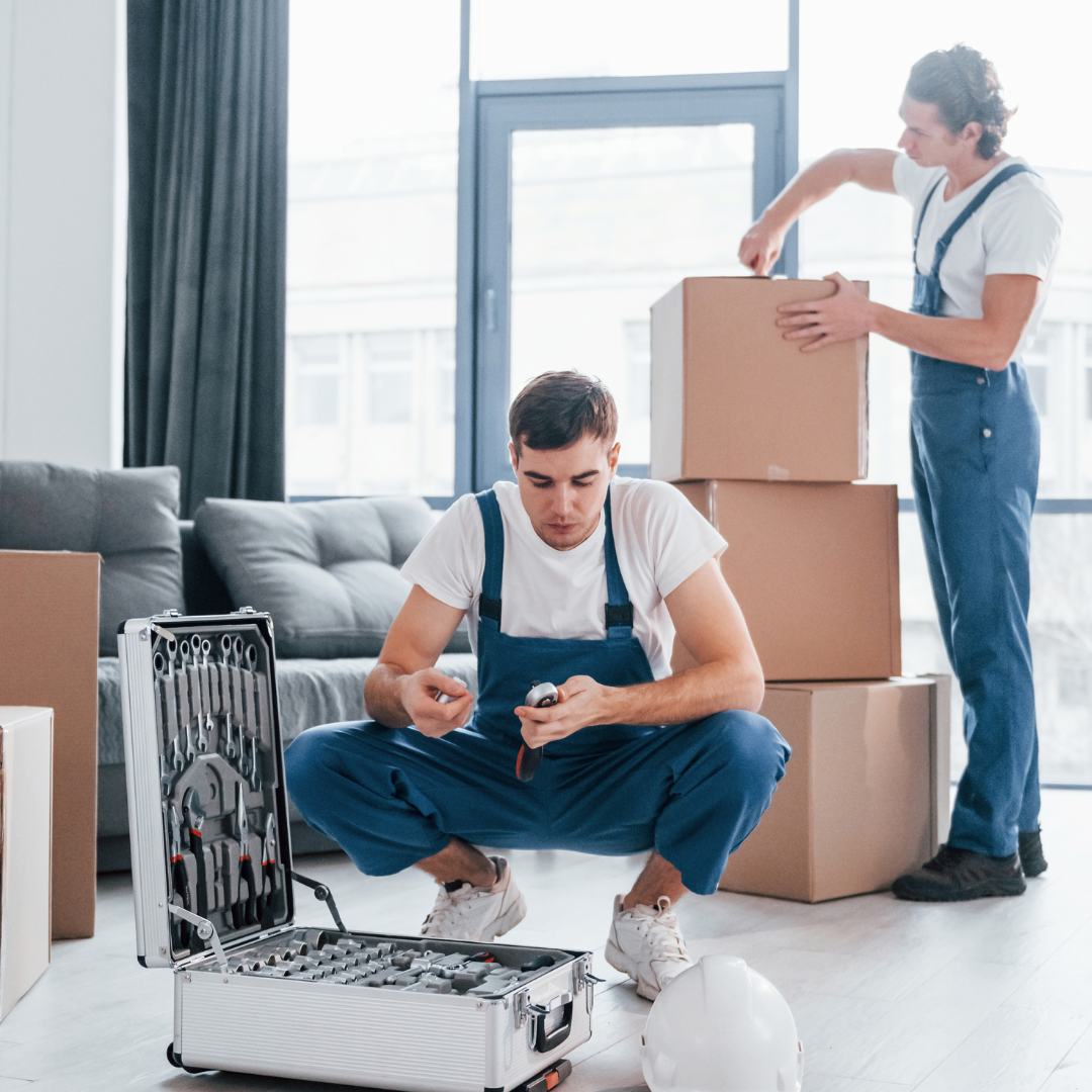 Two movers are carefully packing boxes, ensuring that all items are securely wrapped.