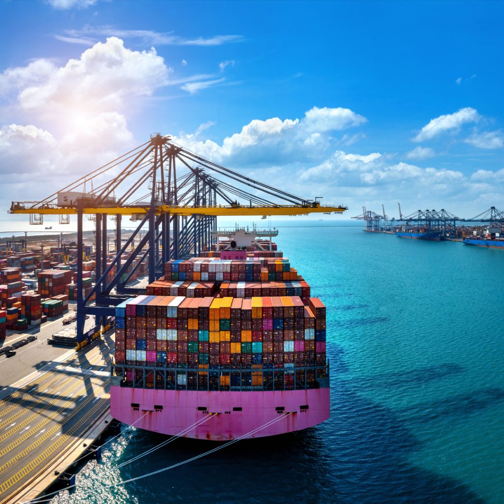 Cargo ship at a seaport, loaded with containers, representing cargo to Pakistan from Dubai.